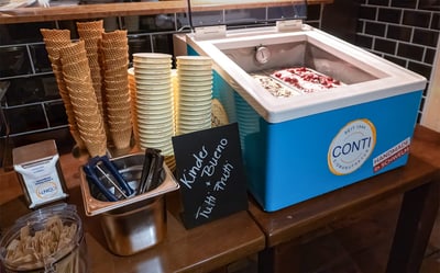 Conti-Eistruhe mit zwei Eissorten, daneben Waffeln, Becher, Löffel und Portionierer