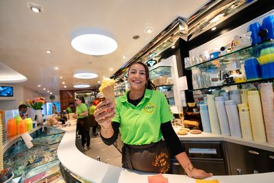 Mitarbeiterin reicht eine frisch gefüllte Eiswaffel über die Theke